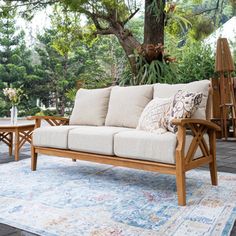 a wooden couch sitting on top of a blue rug next to a table and chairs