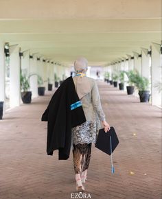 the woman is walking down the walkway with her coat over her shoulder and purse in hand