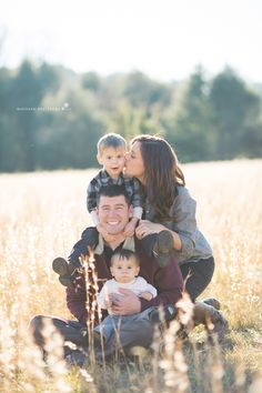 a man, woman and child are sitting in the middle of a field with tall grass