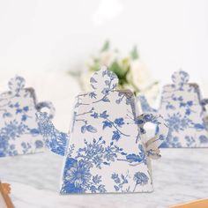 three blue and white ceramic figurines sitting on top of a marble table with flowers in the background