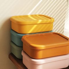 three different colored containers sitting on top of a wooden shelf