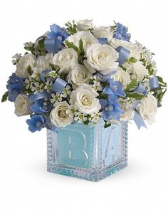 a blue and white bouquet in a square glass vase on a white background with the letter b