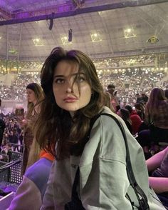 a woman sitting in front of a crowd at a concert with her hand on her hip