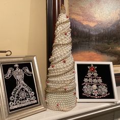 a christmas tree made out of pearls next to two framed pictures