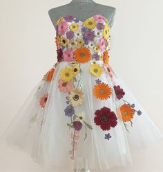 a white dress with colorful flowers on the front and back, sitting on a mannequin