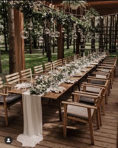 a long table with white linens and greenery is set for an outdoor dinner