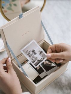 a person is holding an open box with photos inside and the lid opened to show them