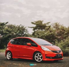 a small red car parked in front of some trees