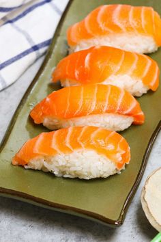 three sushi on a green plate with chopsticks next to it and a bowl of rice