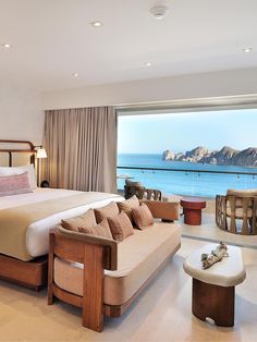 a large bed sitting in a bedroom next to a window with a view of the ocean