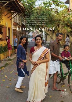 a woman in a white sari walking down the street with two men and a child