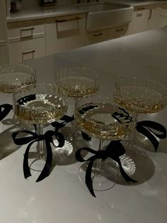 four wine glasses sitting on top of a counter with black ribbon around the rims