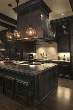 a large kitchen with an island in the middle and lights hanging from it's ceiling