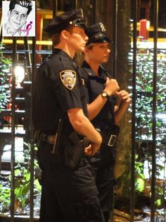 two police officers standing next to each other in front of an iron fence and gate