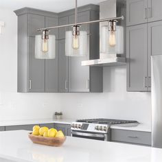 a bowl of lemons on a kitchen counter with three lights hanging over the island