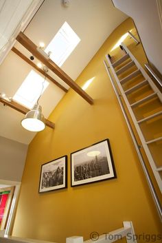 two framed pictures hang on the wall next to a stair case in a room with yellow walls