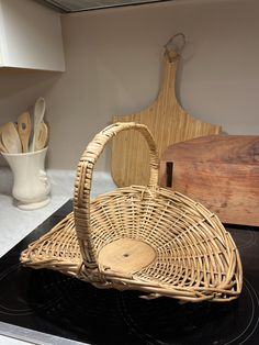 a wicker basket sitting on top of a stove next to cutting board and utensils