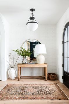 a living room with a rug, table and lamp on the floor next to an arched doorway