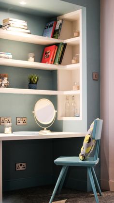 a blue chair sitting in front of a desk with books on it and a mirror