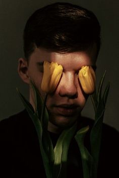 a man with two yellow flowers in front of his face