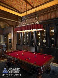 a pool table in the middle of a room with red curtains and chandelier