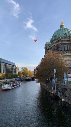 there is a red hot air balloon flying over the water in front of some buildings