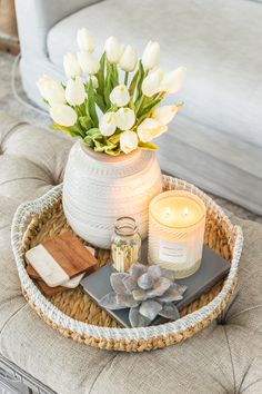 a tray with candles, flowers and other items on it sitting on a couch in a living room