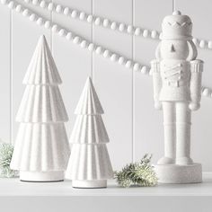 three white ceramic christmas trees and a nutcracker