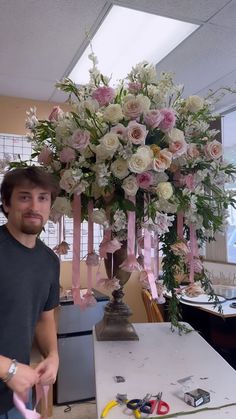 a man standing in front of a flower arrangement with pink and white flowers on it