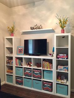 there is a television on top of the bookshelves in this room with blue bins