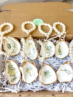 a box filled with lots of decorated cookies in the shape of seashells and pearls