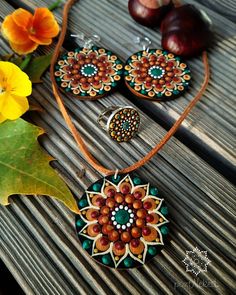 a necklace and earring are sitting on a wooden table next to some orange flowers