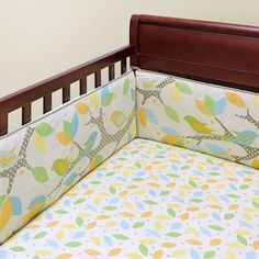 a baby crib with a colorful bedding and pillow on top of it's headboard