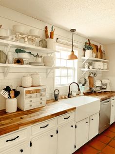 a kitchen filled with lots of white cupboards and counter top next to a window