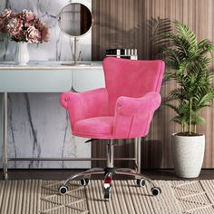 a pink office chair sitting in front of a desk with a mirror and potted plant