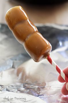 a person holding a candy cane with caramel on it