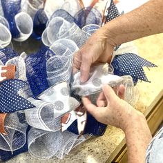 two hands are decorating a football wreath with blue and white mesh bows on it