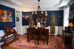 the dining room is decorated for christmas with blue walls and white trimmings on the windows