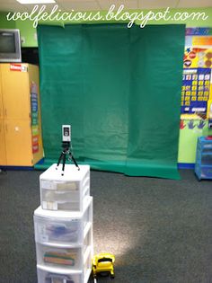 a room with green walls and toys on the floor in front of it is a photo booth set up