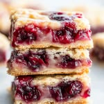 three pieces of berry cheesecake stacked on top of each other with the rest of the cookie in the background