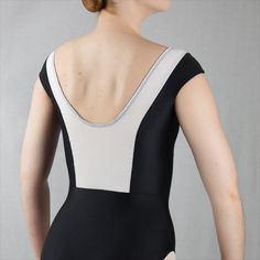 a woman in a black and white leotard with her back to the camera