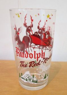 a glass with rudolph the red - nosed reindeer on it sitting on a wooden table