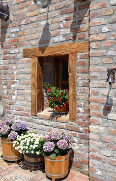 three wooden buckets filled with flowers sitting in front of a brick wall next to a window