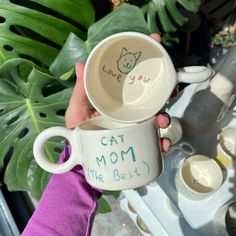 a person holding a coffee cup with the words love you written on it and a cat mom mug