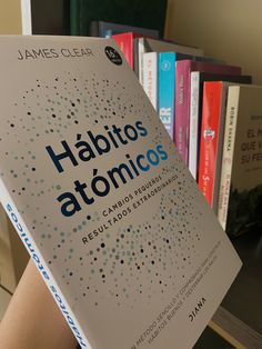 a person holding up a book in front of bookshelves