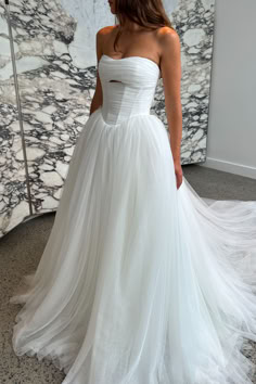 a woman in a white wedding dress is looking at her own reflection on the wall