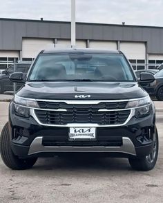 the front end of a black suv parked in a parking lot next to other cars