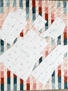 two pieces of paper are laying on top of a quilted tablecloth that has red, white and blue strips