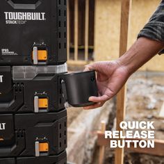 a man holding a cup in his hand next to a construction site with the words toughbuilt stacked on it