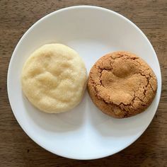 two cookies on a white plate sitting on a wooden table